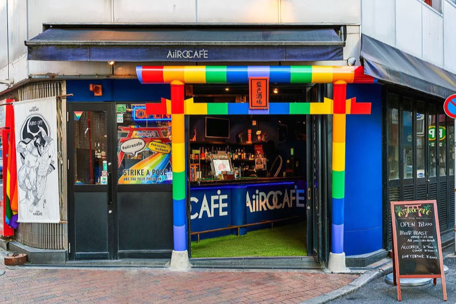 Exterior of AiiRO Café featuring rainbow-themed signage, pride flags, and a welcoming open door to the bar.