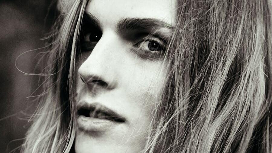 Black-and-white portrait of model Andreja Pejić, gazing at the camera with soft lighting and natural background.