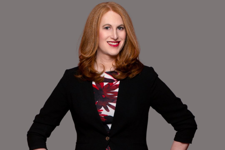 Ashley T Brundage poses in a black blazer and floral dress, featured guest on The Impact Series.