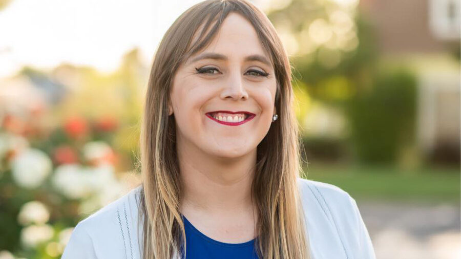 Portrait of Brianna Westbrook in a white blazer and blue top, standing in sunlight.