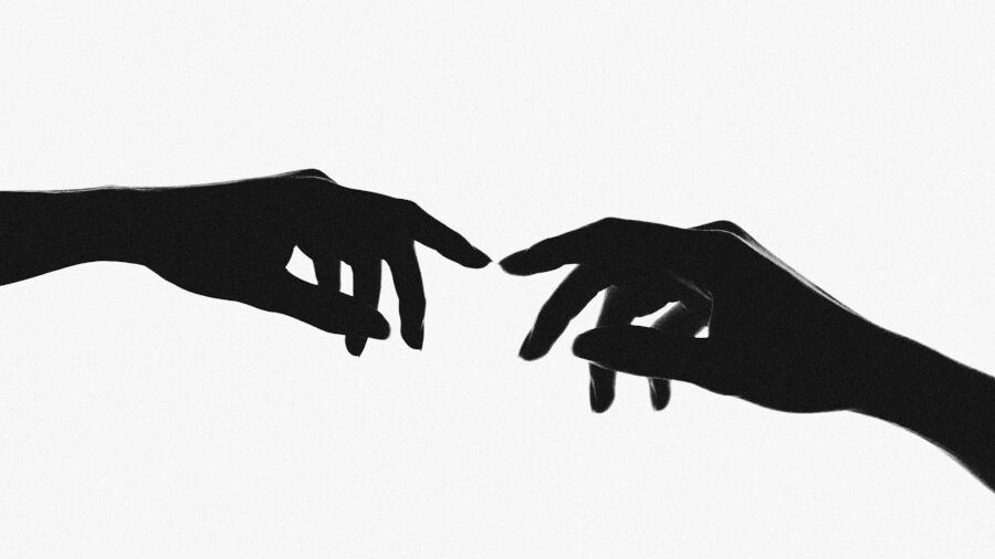 Black silhouettes of two hands facing each other with fingers extended, suggesting a moment of near contact.