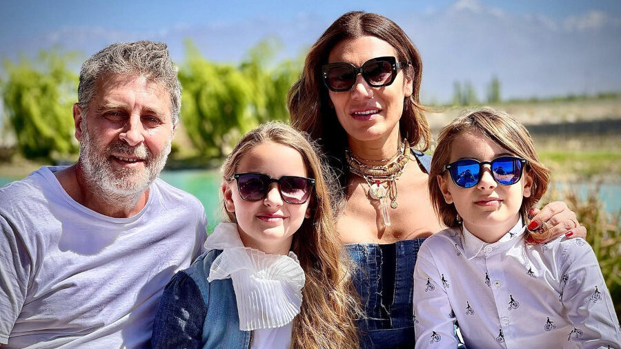 Florencia de la V sourit avec son mari et leurs jumeaux à une table en extérieur, tous en lunettes de soleil.