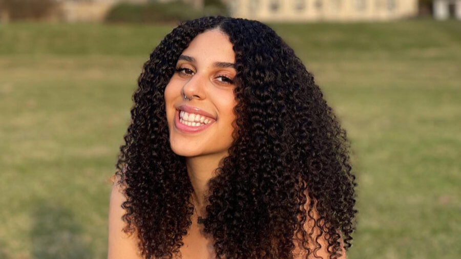 Retrato de Grace Dolan-Sandrino sentada sobre el césped, con edificios al fondo.