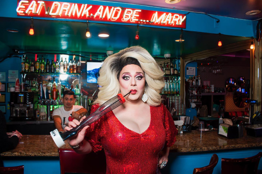 A drag queen in a red sequin dress poses at the bar of Hamburger Mary’s, a festive and LGBTQ+ inclusive venue.