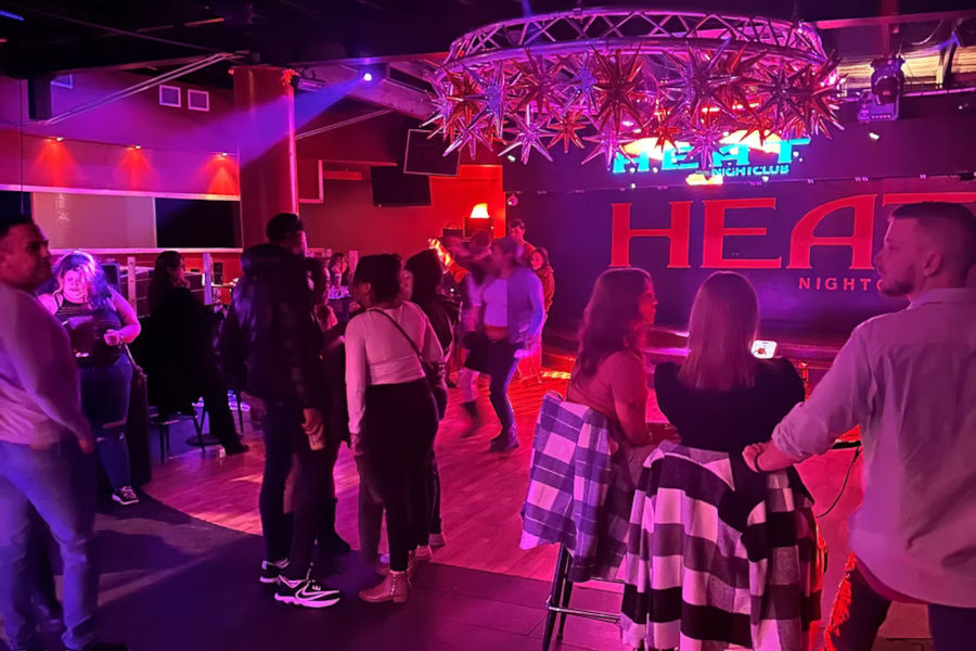 Lively night at Heat nightclub in San Antonio, with people dancing and chatting under colorful lights and decor.