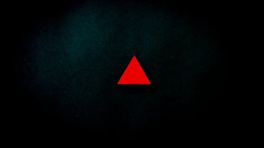 Centered red triangle on a dark textured background with shadowed edges.