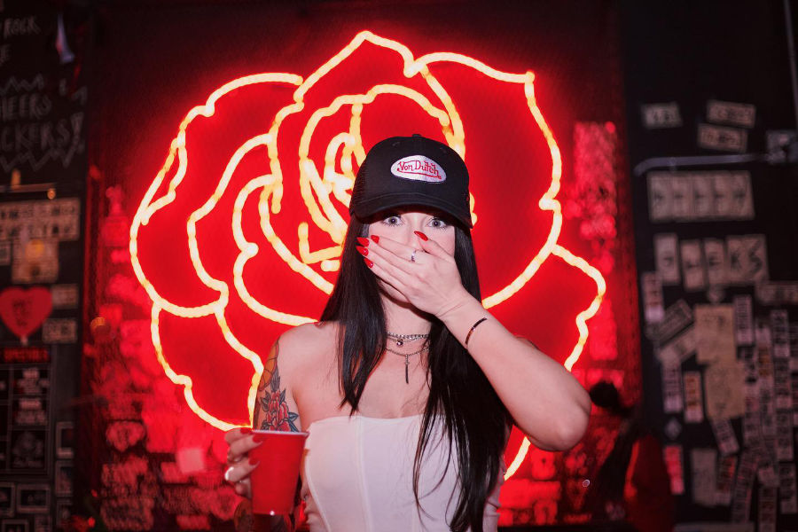 Nightlife scene at Las Rosas Miami, featuring a woman covering her mouth with a red neon rose behind her.