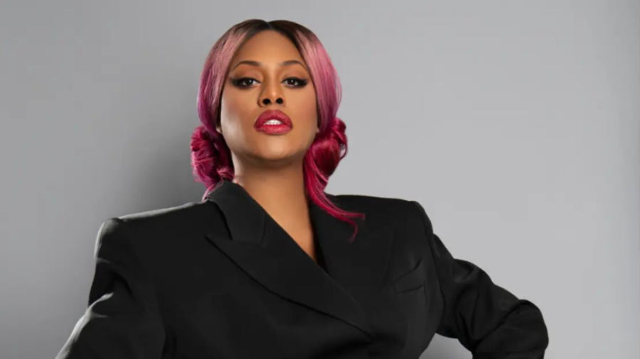 Laverne Cox con un blazer-vestido negro entallado con cortes, posando con confianza.