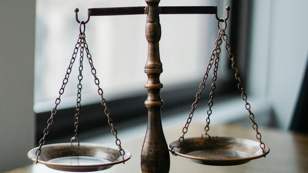 Balanza de latón antigua equilibrada con cuencos poco profundos, colocada en un interior cerca de una ventana.