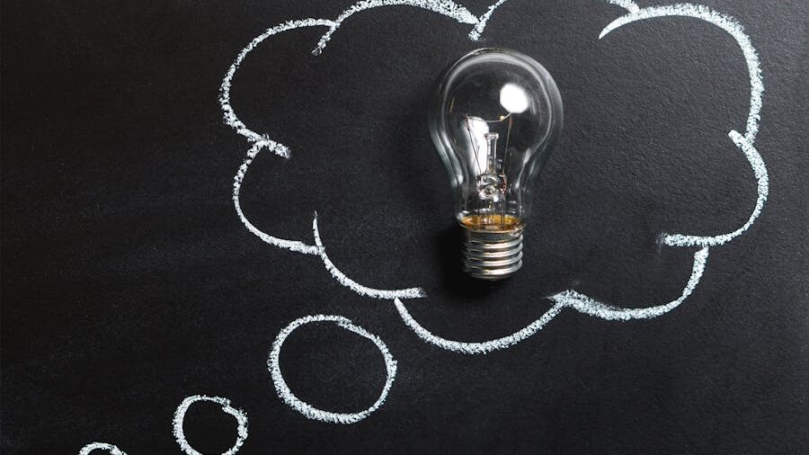 A lightbulb placed inside a chalk-drawn thought bubble on a blackboard, symbolizing a new idea or inspiration.