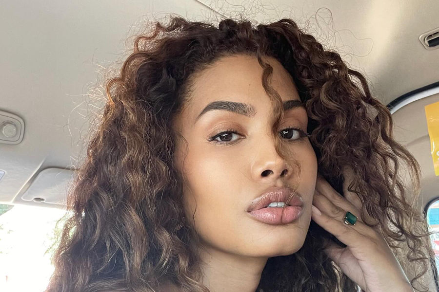 Leyna Bloom posing in a car, curly hair and necklace visible, taken in Placencia, Belize in early 2024.