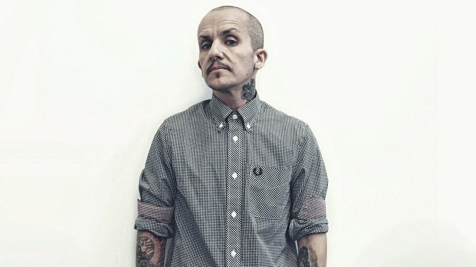 Lucas Silveira debout devant un mur blanc, portant une chemise Fred Perry pour la campagne Anchor.