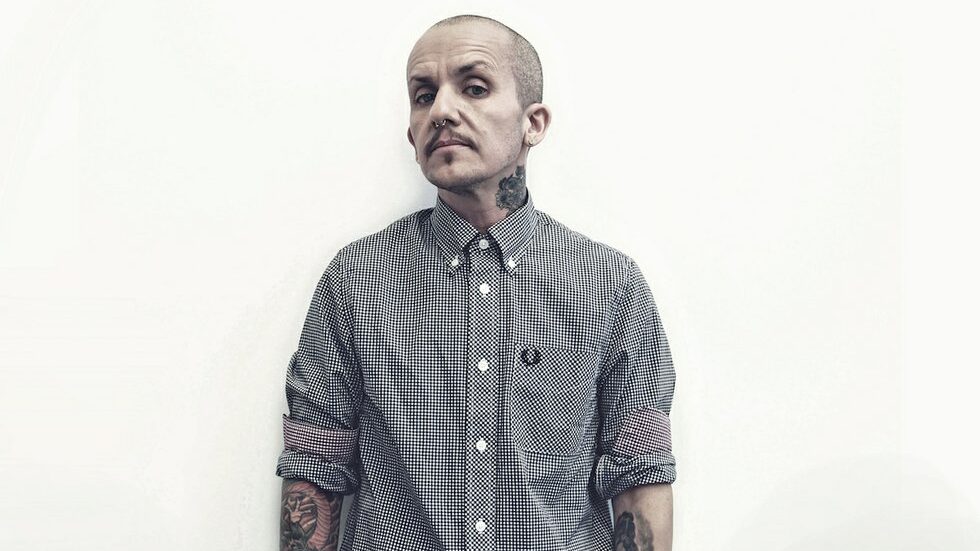 Lucas Silveira de pie frente a una pared blanca con camisa Fred Perry, posando para la campaña Anchor.