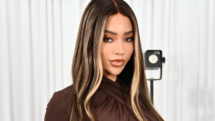 Portrait glamour de Munroe Bergdorf avec de longs cheveux méchés et une robe marron modifié en studio.