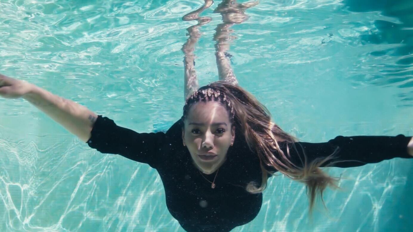 Promotional image of Munroe Bergdorf underwater with outstretched arms.