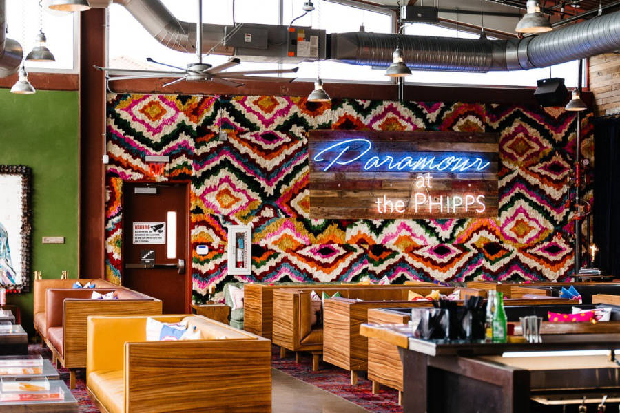 Lounge view of Paramour at the Phipps in San Antonio, with booths, colorful art, and neon signage.