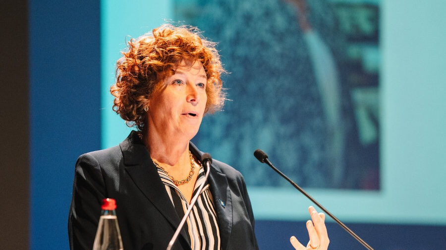 Petra De Sutter at a tech conference in Ghent, wearing a dark blazer and striped blouse.