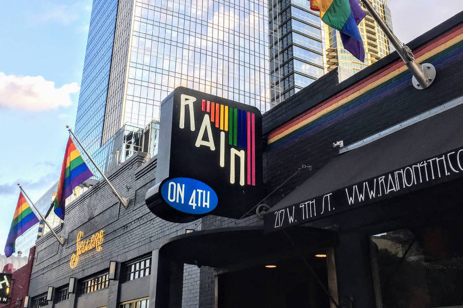 Exterior photo of Rain on 4th LGBTQ nightclub in Austin, Texas, showing rainbow flags, signage, and colorful stripes on the building.