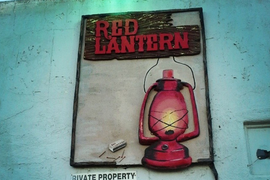 Sign for The Red Lantern LGBTQ+ bar in Fresno, showing a glowing red lantern painted on a weathered wall.