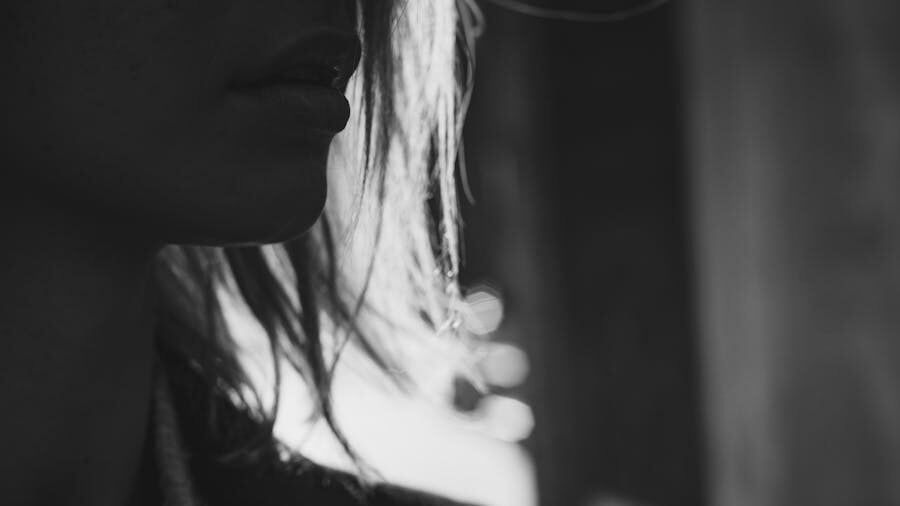 Close-up of a person’s lips and nose in shadow, expressing emotion and introspection.