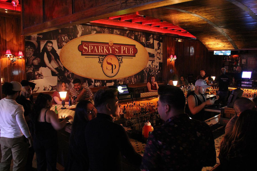 A crowd enjoys drinks at Sparky’s Pub in San Antonio, a cozy English-style bar, during a warm night.