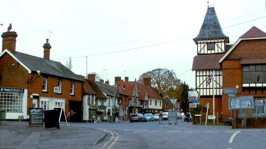A 2006 street view of Lower Street in Stansted Mountfitchet, Essex, showing traditional buildings and road signs.