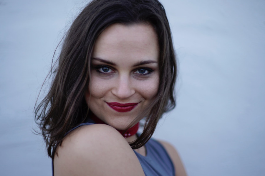 Smiling transgender woman from Sacramento, posing confidently with dark hair and bold red lipstick.