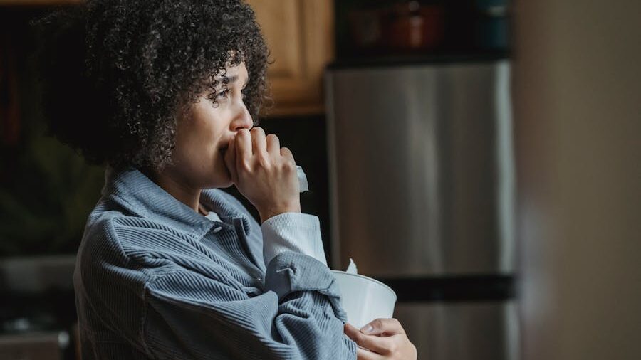 Una mujer sostiene un pañuelo descartable en una cocina en actitud pensativa.