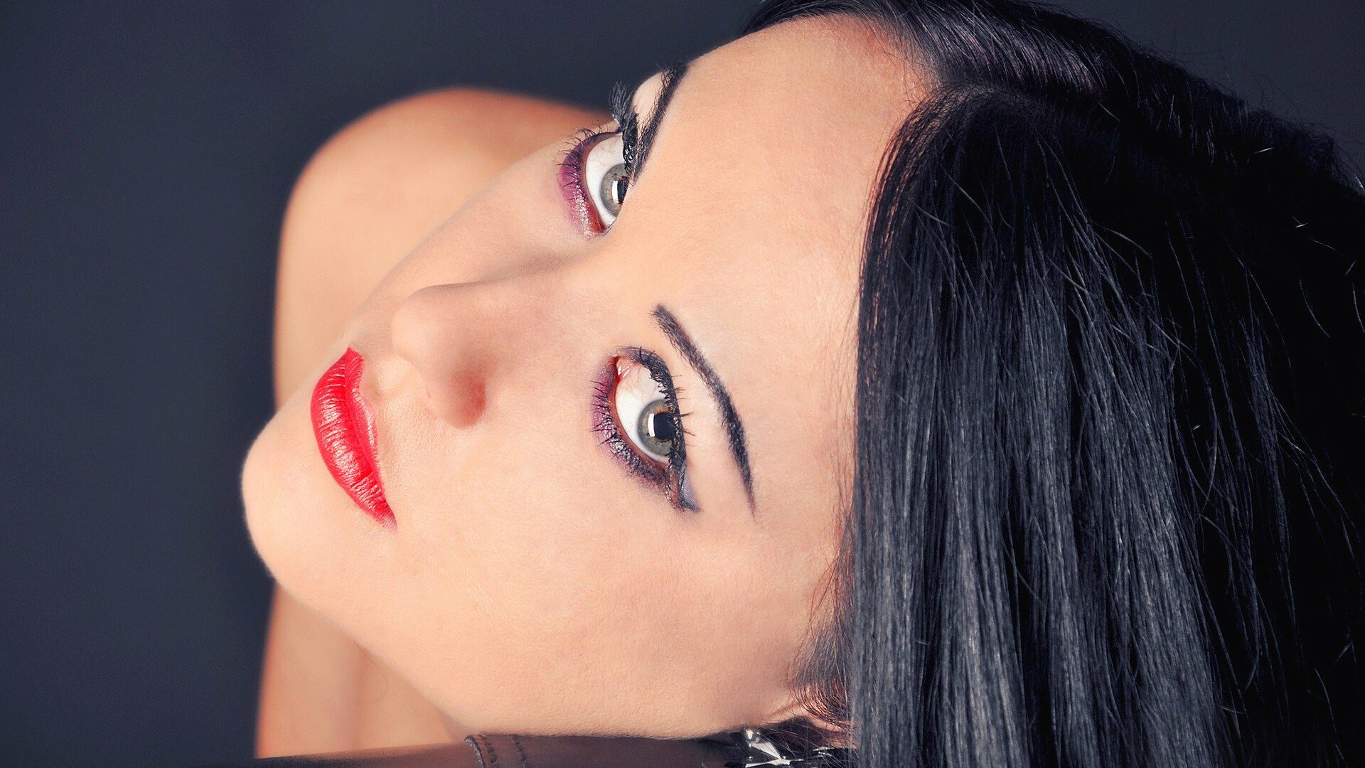 Woman with striking makeup and red lips, captured in a close-up portrait.
