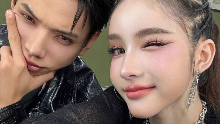Yoshi Rinrada smiling with braided hair and statement jewelry next to a male friend.